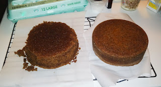 Picture of two cakes that are cooling on wire rack after they have been taken out of the cake pans. The left one has cake crumbs all around it and is misshapen.