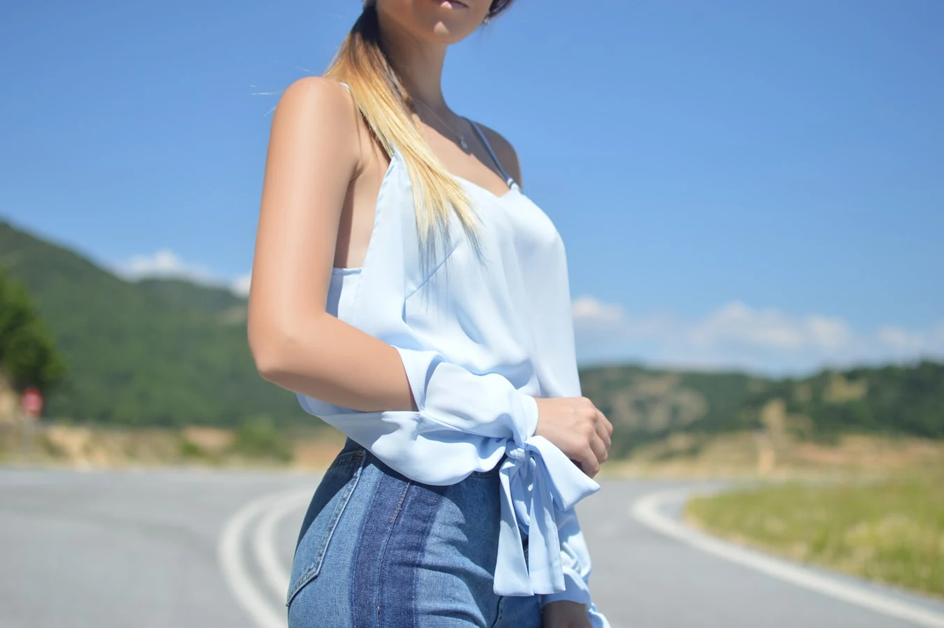 girl in camisole top and jeans is posing on a street