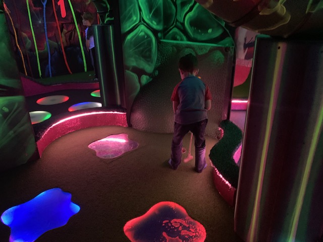 Boy playing crazy golf with neon lighting