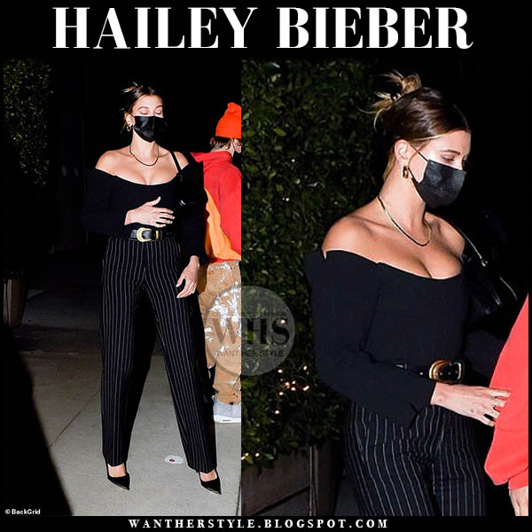 Hailey Bieber in black off shoulder top and black striped trousers