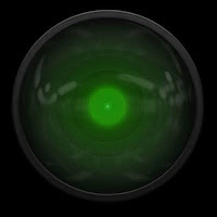 A dark, green, glassy circle. A mechanical iris in which a green light glows. It's looking at you. Probably.