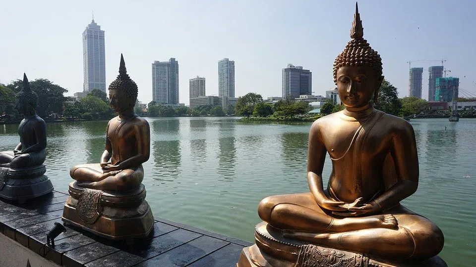 Три статуи Будды на фоне озера Бейра. На втором плане— здания Всемирного торгового центра