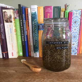 Jar of lavender oil sat on a wooden worktop in front of a row of coloured cooking books