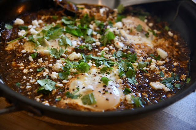 chipotle barbacoa in a skillet, topped with eggs, cotija cheese and cilantro