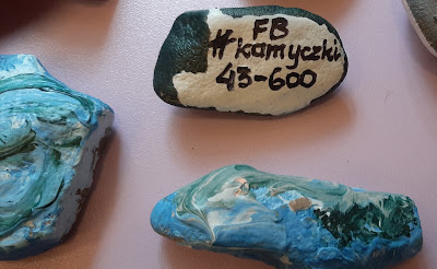 Na jasnym tle 3 kamienie. Na kamykach widać na rewersie napis FB #kamyczki 43-600 a na awersie jest kolorowa twórczość pań z Klubu Babski Magiel.