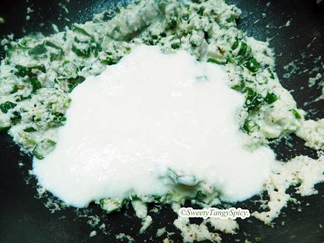 Adding curd to the mixed ingredients in a pan.