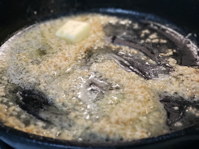 Cooking minced garlic in olive oil in a cast iron skillet.