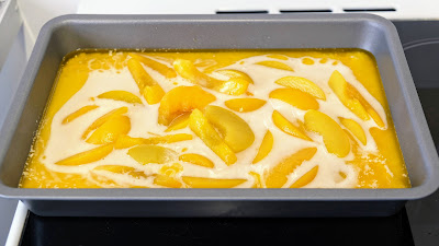 Raw Peach Cobbler in a metal baking dish