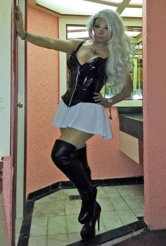 Sexy crossdresser posing in white mini skirt, boots and pantyhose