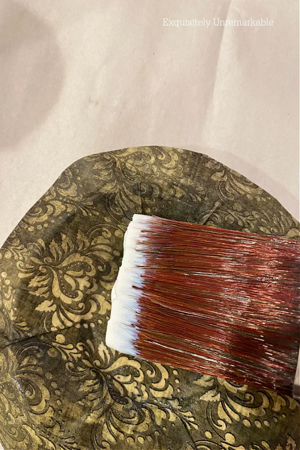 Brushing decoupage gel over rice paper on a plate