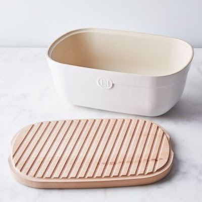 ceramic bread bin with lid sitting next to it, showing the grooved cutting board side of the lid