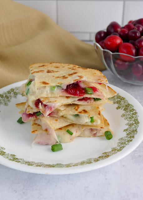 a stack of cut quesadillas on a white and green plate.