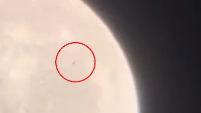Black UFO circled in red flying across the Moon.