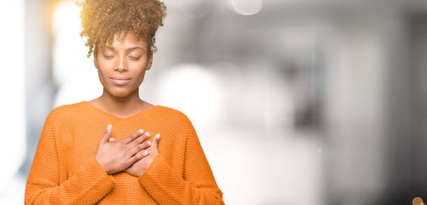 Joyful African American woman with closed eyes, expressing gratitude and self-appreciation.