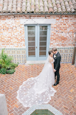 bride and groom standing in casa feliz courtyard with long lace veil
