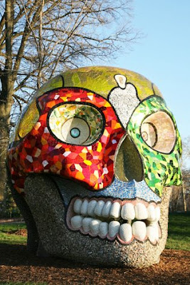 This six-ton smiling skull was inspired by a trip Niki made to Mexico in the late 1970s. She liked the cheerful way in which Mexicans deal with the subject of death. -- The Mexican tradition of the Day of the Dead seems to inform La Cabeza as a face of death that is both festive and contemplative. It pulls viewers in as it reflects life back. -- The piece is an inventory of the materials Niki used, from mother of pearl, to geometric mirrored glass, to the translucent round glass pieces that she called M&M's. This skull is fully interactive and easily accessible. -- Go inside to look around or have a seat in its domed meditation room, with its blue sky and moon.