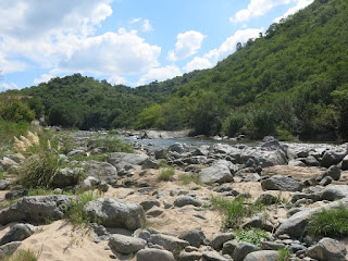 Stream amid green hills and blue sky