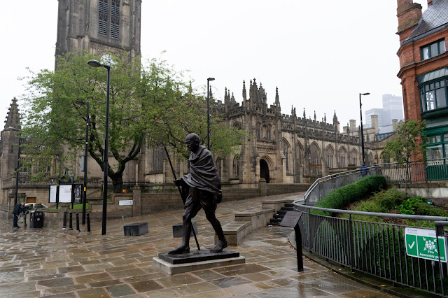 Gothic cathedral building on misty day with statue of Gandhi in foreground