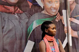 African woman standing in front of a University postrer