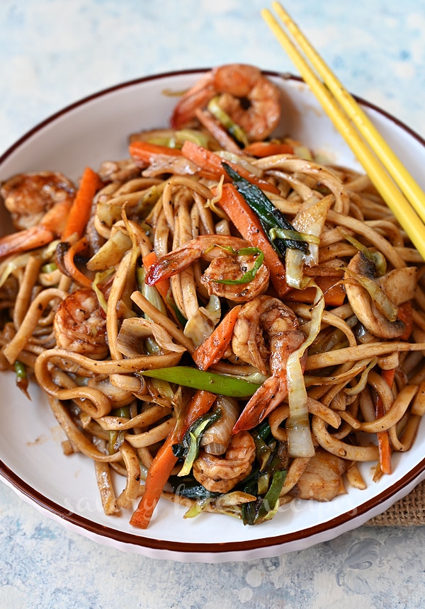 a close look of a white plate with yaki udon with shrimp