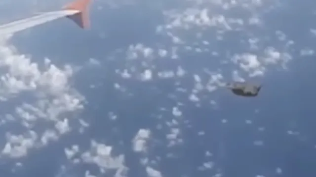 Grey military like craft filmed from the window of an airplane over Poland.