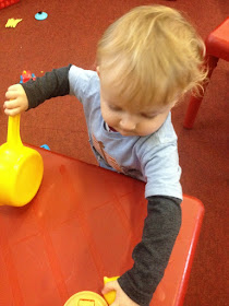 Toddler playing with toy saucepan and concentrating hard