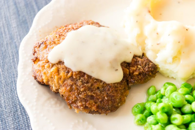 chicken fried steak with potatoes, gravy and peas