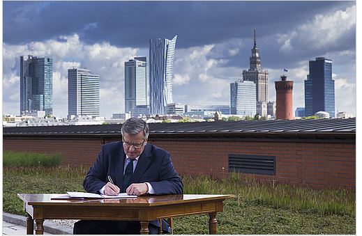 Prezydent Bronisław Komorowski podpisuje ustawę na tle panoramy Warszawy