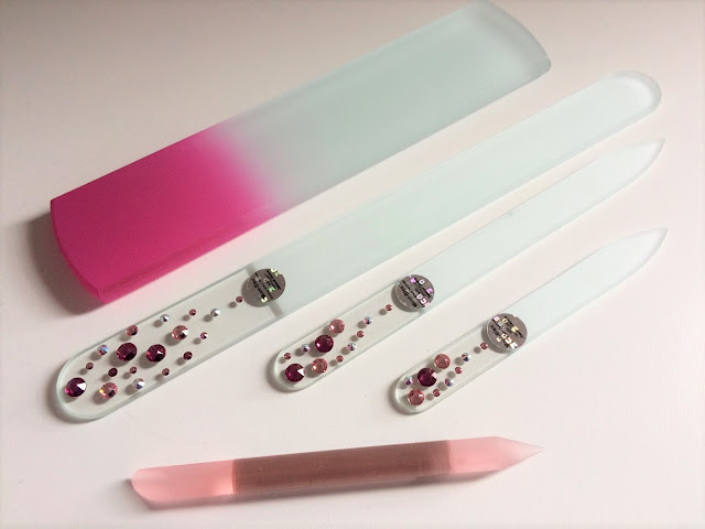 pale pink cuticle pusher, deep pink and clear glass foot scraper and three (small medium and large) glass nail files with pink and light pink swarovski crystals against white background