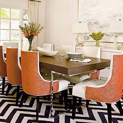 colorful orange chairs in dining room with black white chevron rug