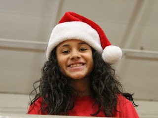 Young girl in a red shirt smiling wearing a red Santa hat