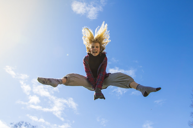Young girl jumping in the air, looking down at you