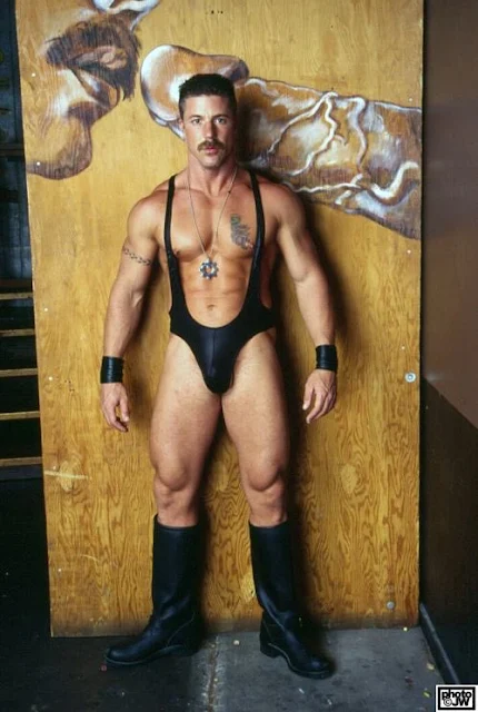 Handsome muscular tattooed daddy with a mustache wearing black leather wrestling uniform