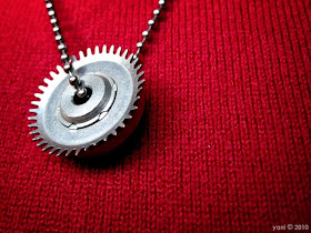 cog pendant against red sweater... hard and cold versus soft and warm