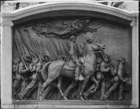 A relief showing a man on horseback surrounded by other on foot, all carrying bayonets. A draped female figure flies above them.