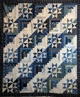 Alternating blue and white Ohio Star and Log Cabin blocks with a navy ikat border