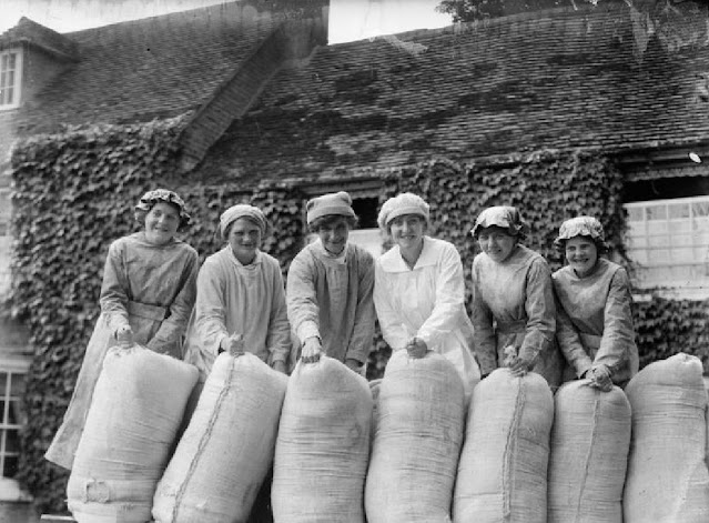 Группа улыбающихся работниц позирует с мешками с мукой
