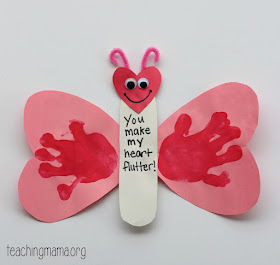 pink construction paper butterfly wings with handprint stamped on  and popsicles stick craft for preschoolers to make for Valentine's Day
