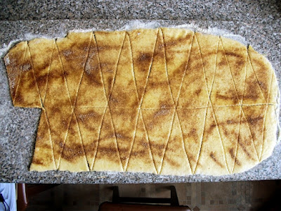 A kifliknek való tészta megszórva mézeskalács fűszerkeverékkel, és háromszögekre vágva.