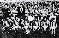 REAL BETIS BALOMPIÉ - Sevilla, España - Temporada 1976-77 - Esnaola, Bizcocho, Szusza (entrenador), Biosca, Sabaté, López y Cobo; Megido, Muhren, Ladinsky, Cardeñosa y Anzarda - REAL BETIS BALOMPIÉ 5 (Ladinsky, Megido y Anzarda 3), ESPAÑOL 1 (Marañón) - 31/10/1976 - Liga de 1ª División, jornada 8 - Sevilla, estadio Benito Villamarín - 5º clasificado en la Liga, con Rafa Iriondo de entrenador, que en la jornada 9 sustituyó a Szusza, el Betis ganó esta temporada la Copa del Rey