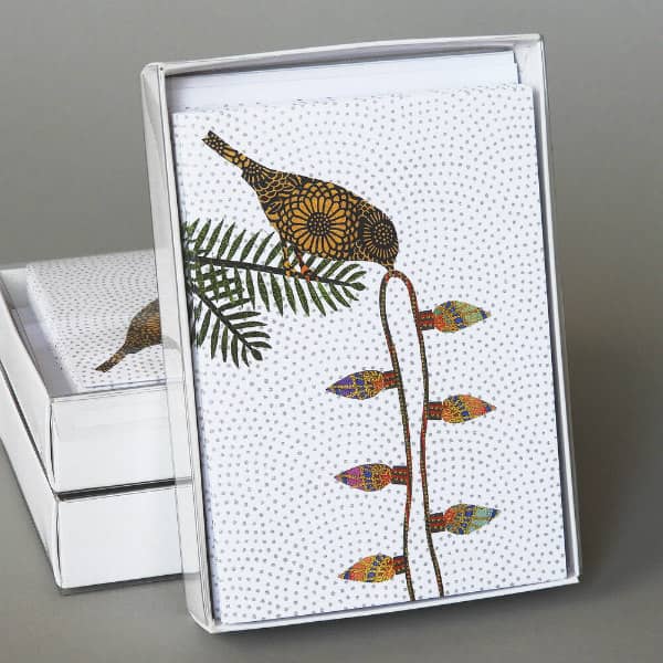 patterned paper collage of bird holding string of lights in beak on card front alongside stack of two greeting card boxes
