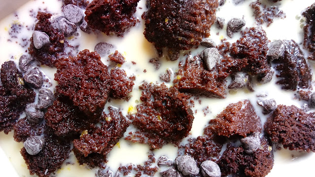 a close up of the unbaked bread pudding - crumbled chocolate cupcakes and chocolate chips sitting in custard mixture