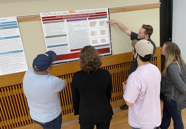 Student pointing to poster explaining results they found to other students