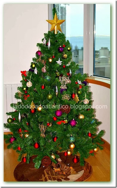 Imagem de um Pinheiro grande de Natal com muitos ornamentos e uma estrela dourada no topo