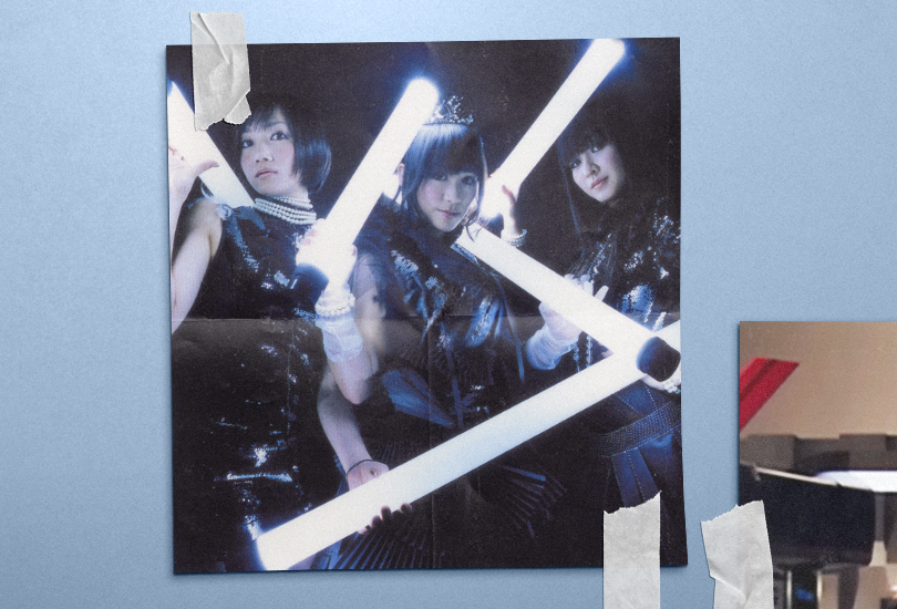 An image featuring the Limited Edition cover of Perfume’s first studio album, Game. Which features all 3 members (from Left to Right: Nocchi, a-chan, Kashiyuka) all in black Gothic Lolita style outfits, holding white fluorescent tube lights.