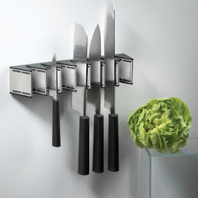 stainless steel wall-mounted knife rack, holding four knives so the blades face the wall