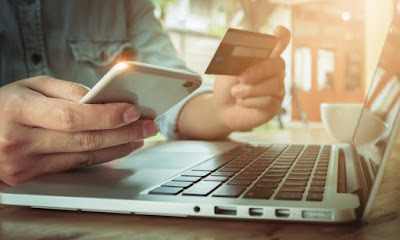 eCommerce store owner working with a smart phone, credit card and a computer.