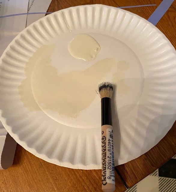 Photo of a paper plate with a spoonful of paint and a stencil brush