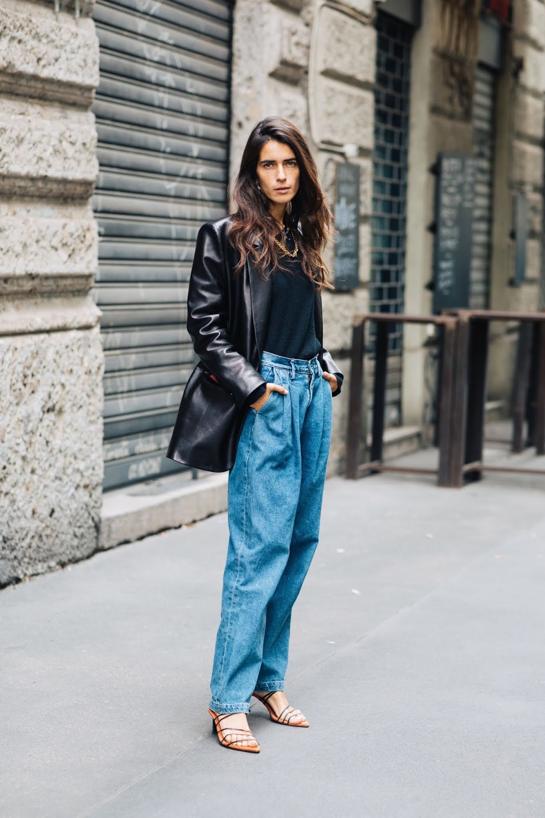 How to Wear 80s-Inspired Pleated Jeans — Street style outfit with black leather blazer, gold chain necklace, denim, and strappy sandals