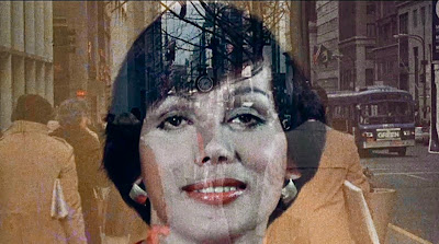 In a scene from let me die a woman, a dark haired trans woman faces the camera with a smile as a city landscape dissolves in the background